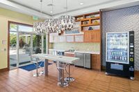 The Marq at Highland Park High Top Seating Space at Apt CoWork at The Marq at Highland Park Apartments in Westchase Tampa Coworking space with kitchen and snack station with elegant pendant lighting, sleek countertops, and a convenient vending machine, opening to a sunny outdoor patio at the Marq Highland Park Apt CoWork in Westchase Tampa