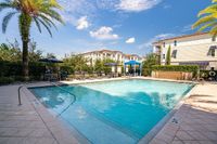 The-Marq-Highland-Park-Apartments-Pool-Area-in-Westchase-Tampa-Florida Luxurious apartment complex featuring a sparkling outdoor pool, sun loungers, and shaded seating areas under blue skies at The Marq Highland Park Apartments in Westchase Tampa