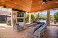 The-Marq-Highland-Park-Apartments-Outdoor-Lounge-By-Pool-in-Westchase-Tampa-Florida Luxurious outdoor lounge with elegant seating, modern TV setup, and view of a sparkling pool surrounded by lush greenery at The Marq Highland Park Apartments