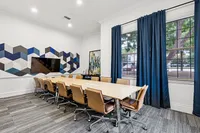 Modern conference room with a sleek long table, comfortable leather chairs, and a vibrant geometric wall design.