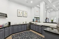Elegant kitchen in coworking space with sleek black countertops, modern cabinetry, and artistic wall decor at Stonebriar at Frisco Apartments