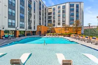 Luxurious apartment complex with a sparkling resort-style swimming pool surrounded by chic lounge chairs and modern architecture at Cottonwood Westside Apartments in West Midtown