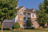 Charming apartment building, The Stratford at Hillcrest Towne Center Apartments, with classic brick facade and cozy balconies, surrounded by lush greenery in a serene neighborhood.