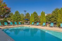 Inviting outdoor pool with vibrant lounge chairs and lush greenery, perfect for relaxation and entertaining at The Stratford at Hillcrest Towne Center Apartments.