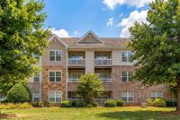 Charming apartment building with stone and brick facade, surrounded by lush greenery and vibrant trees at Stratford at Hillcrest Apartments in Winston-Salem.