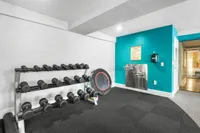 Modern fitness center at Cottonwood Westside with a diverse set of dumbbells, vibrant blue accent wall, and a cozy corner trampoline.