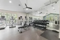 Modern fitness center equipped with state-of-the-art cardio machines, free weights, and mirrored walls for an invigorating workout experience at Raveneaux Apartments in North Houston