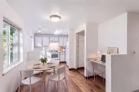 Bright, airy kitchen and dining area with sleek modern design, elegant wood flooring, and a cozy workspace.