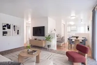 Contemporary living room with stylish furniture, large TV, and an inviting open-plan design leading to a chic dining area and modern kitchen.
