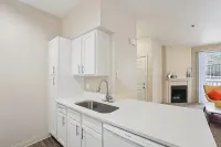 Modern apartment interior showcasing a sleek kitchen with white cabinetry, and a cozy living area with a stylish fireplace and natural light.
