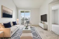 Bright and contemporary living room featuring elegant furnishings, a stylish TV setup, and access to a private balcony with scenic views.