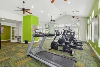 Bright and modern fitness center with treadmills and ellipticals, featuring vibrant green accents and abundant natural light.
