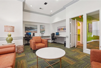Inviting office space featuring modern decor, plush leather seating, vibrant carpet, and functional workspace with computers.
