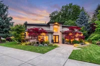 Charming modern home surrounded by lush greenery and vibrant landscaping at sunset.