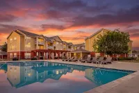Charming sunset view of a lovely apartment complex, The Orchards at Cherry Creek Park, featuring serene poolside relaxation and elegant lounging chairs.