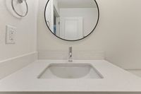 Modern bathroom vanity with sleek white countertop and stylish round mirror, creating a chic and inviting space.