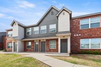 Charming apartment home with modern architecture, featuring red brick and grey siding, set in a peaceful suburban neighborhood.