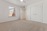Inviting bedroom with plush carpeting, abundant natural light, and modern white accents.