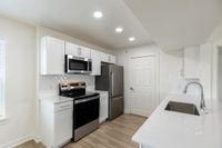 Modern kitchen with sleek white cabinets, stainless steel appliances, and elegant countertops under soft recessed lighting.