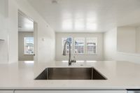 Modern kitchen with sleek countertops and stylish stainless steel faucet, basking in natural light through large windows.
