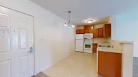 Charming kitchen and dining area with modern appliances, elegant lighting, and warm wooden cabinets in a cozy apartment.