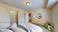 Bright, modern bedroom featuring cozy bedding, ample natural light, and elegant decor with a stylish dresser and a vibrant houseplant.
