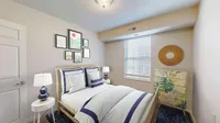 Charming and cozy bedroom with modern decor, featuring a comfortable bed with navy accents, artistic wall prints, and a nature-inspired dresser for a tranquil vibe.