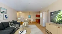 Modern living space with plush grey sofa, elegant dining area, and sleek entertainment setup, inviting natural light and warmth.