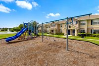 Charming residential community with modern playground, lush greenery, and serene pond backdrop.