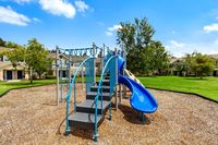 Charming community playground with modern equipment, surrounded by lush green lawns and inviting apartment homes.