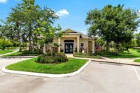 Charming community clubhouse surrounded by lush greenery and vibrant landscaping, set against a clear blue sky.
