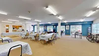 Bright and spacious communal area with dining tables, modern kitchen, and large windows for ample natural light.