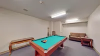 Charming game room with a pool table, cozy sofa, and classic wooden furniture, perfect for entertaining and relaxation.