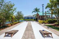 view of corn hole game area located near clubhouse along lake on sunny day