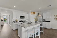 Modern kitchen with island seating, granite countertops, and stainless steel appliances.