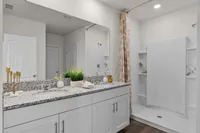 Bright and spacious bathroom with dual-sink vanity and walk-in shower.
