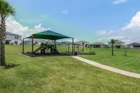 Shaded playground nestled in wide-open green space.