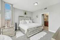 Primary bedroom with large windows, plush carpeting, and mirrored furniture.