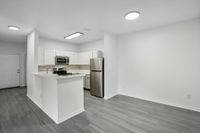 interior pic of deluxe unit kitchen with gray planking and white walls, stainless steel appliances, white cabinets and tile backsplash