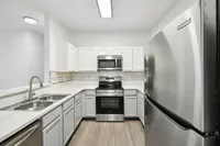 interior pic of deluxe kitchen unit with gray planking and white walls, stainless steel appliances and backsplash