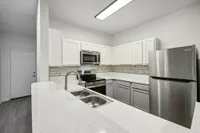 interior pic of deluxe kitchen unit with gray planking and white walls, stainless steel appliances and backsplash