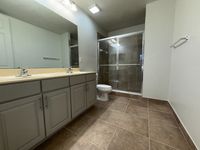 Modern bathroom with elegant double vanity, sleek fixtures, and a spacious glass-enclosed shower.