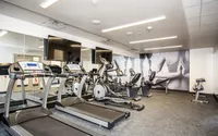 Modern fitness center with cardio machines, weights, and wall-mounted TVs.