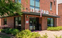 Main entrance to The Pad apartment community with red brick exterior and modern signage.