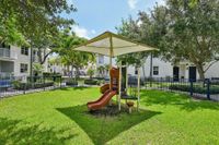 Vibrant playground with slide, surrounded by lush greenery and shade structures.