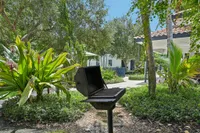 Outdoor patio featuring a barbecue grill surrounded by lush greenery and a cozy seating area.