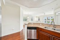 Bright, open-concept living area showcasing sleek granite countertops, stainless steel appliances, and a warm, inviting wooden floor.
