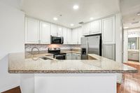 Modern kitchen with sleek granite countertops, white cabinetry, stainless steel appliances, and stylish tile backsplash.