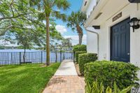 Charming waterfront apartment entrance with lush greenery, palm trees, and serene lake views.