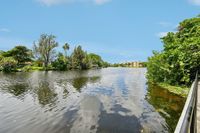 Scenic waterfront view showcasing lush greenery, serene reflections, and modern apartments in a tranquil setting.